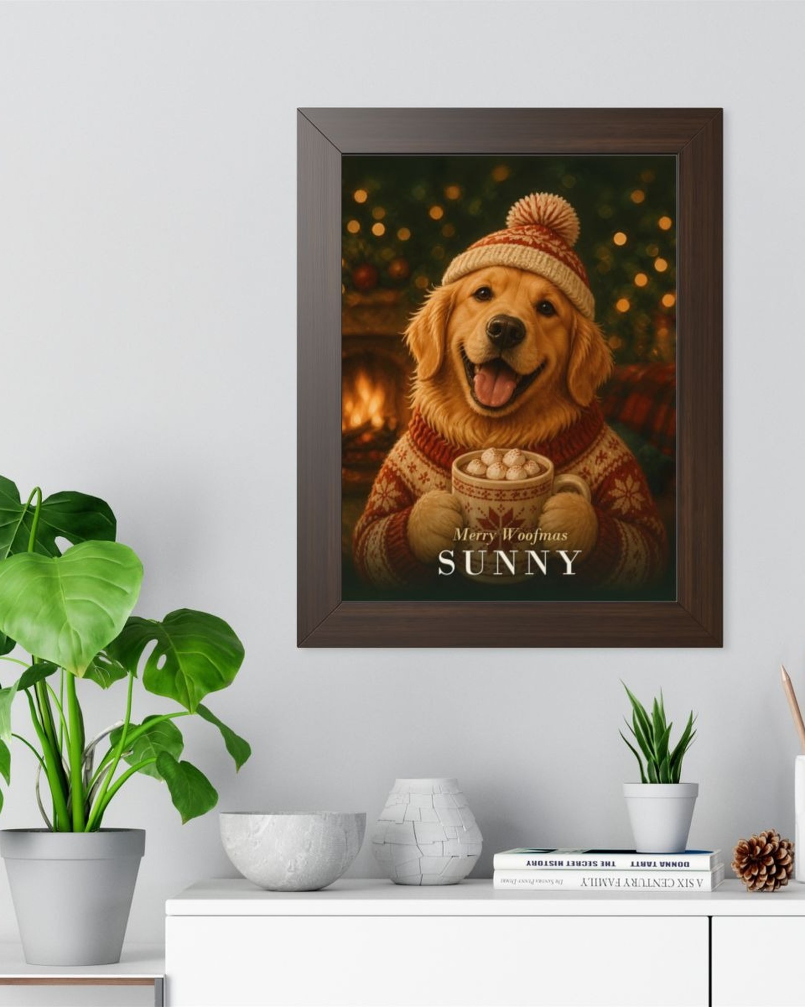 The walnut framed Christmas poster on a light gray wall above a white sideboard with plants