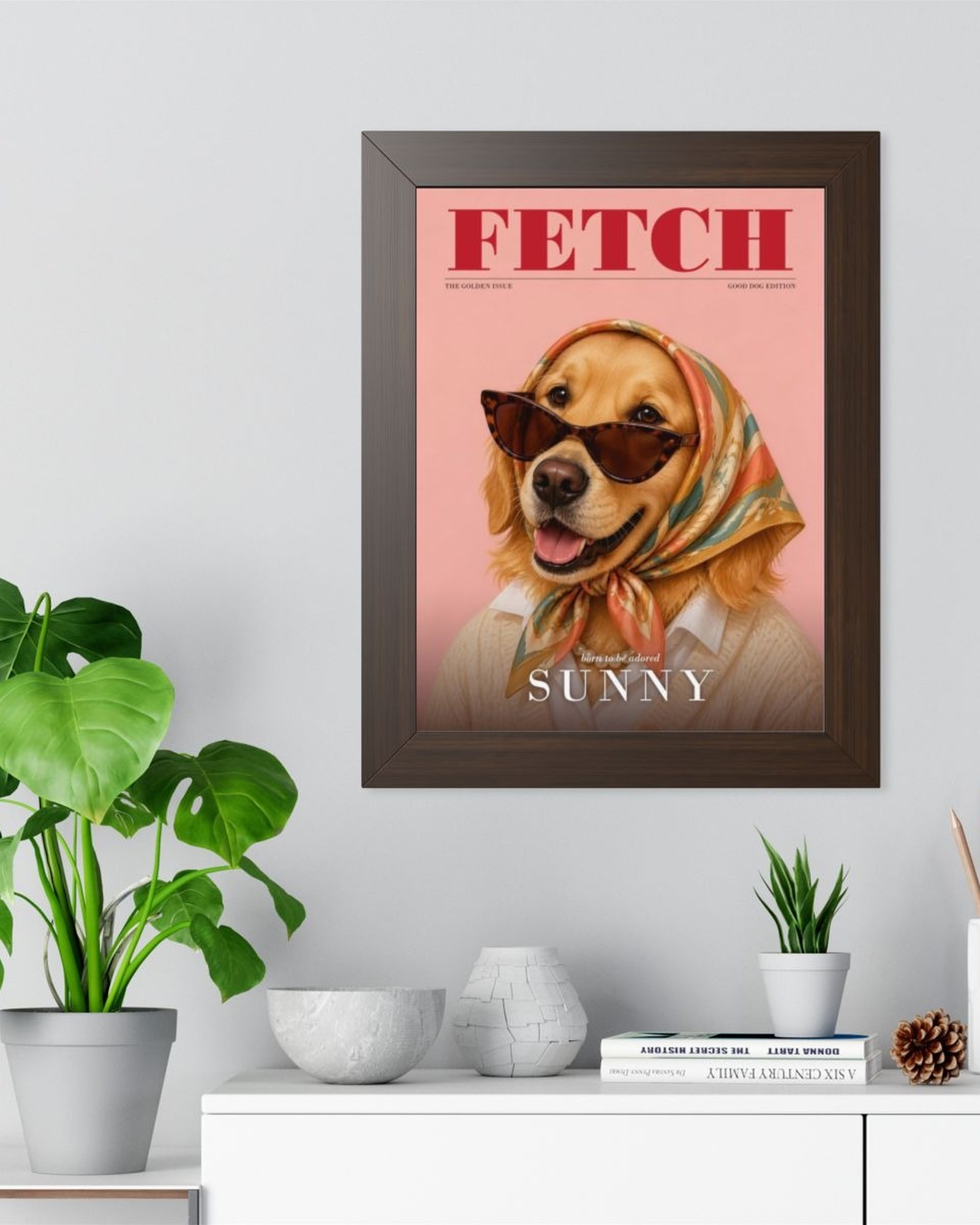 The walnut framed magazine cover poster on a light gray wall above a white sideboard with plants